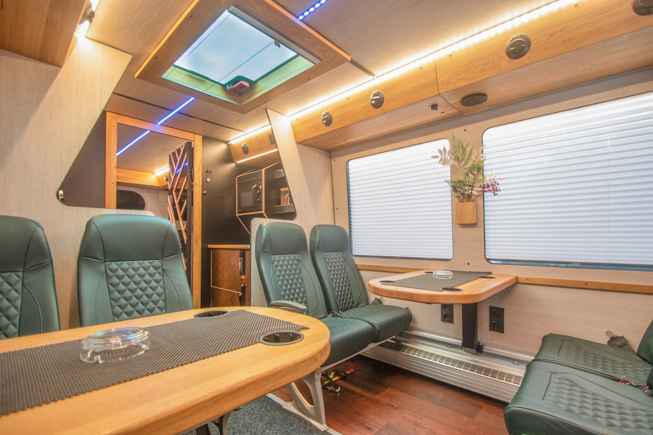 Interior of a tour bus with leather seats, tables and screens