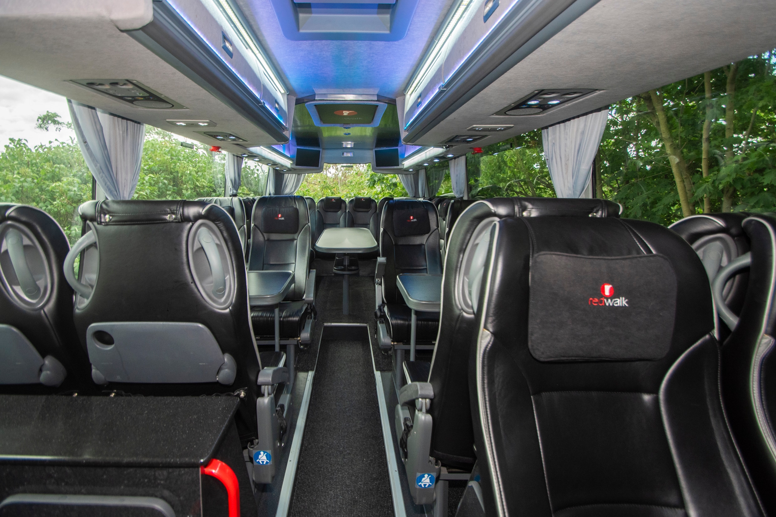 Teambus Van Hool interior: rows of seats and a table along the centre aisle