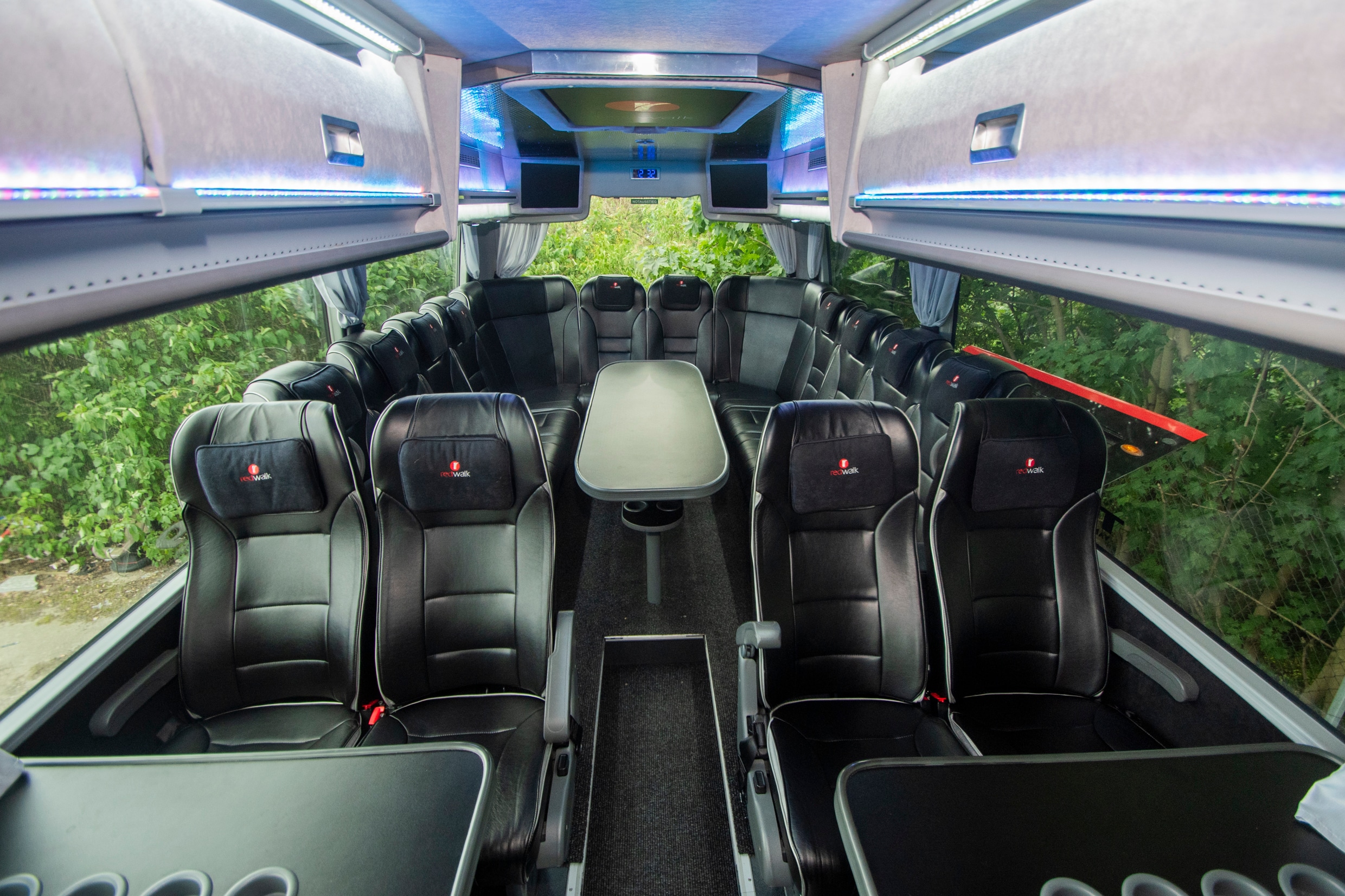 Teambus Van Hool interior: seating groups with tables under blue ceiling lighting